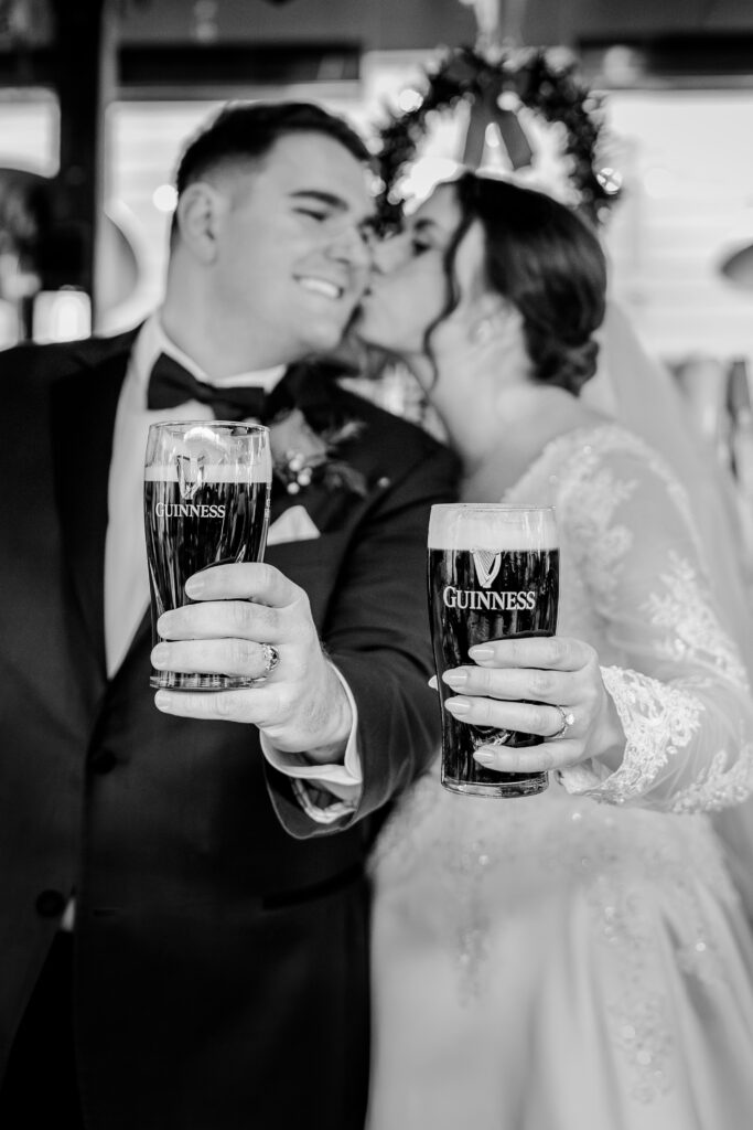 A bride and groom hold out their drinks while showing off their wedding rings during a wedding at Jimmy's Old Town Tavern in Herndon Virginia