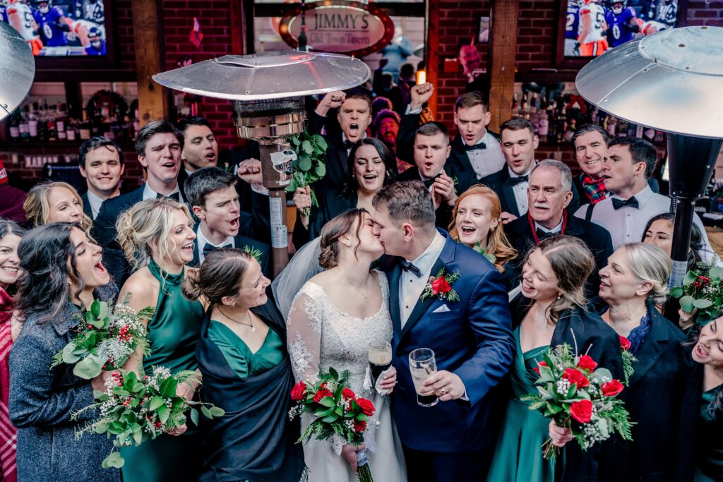 A wedding party cheers as the bride and groom share a kiss at Jimmys Old Town Tavern in Herndon Virginia