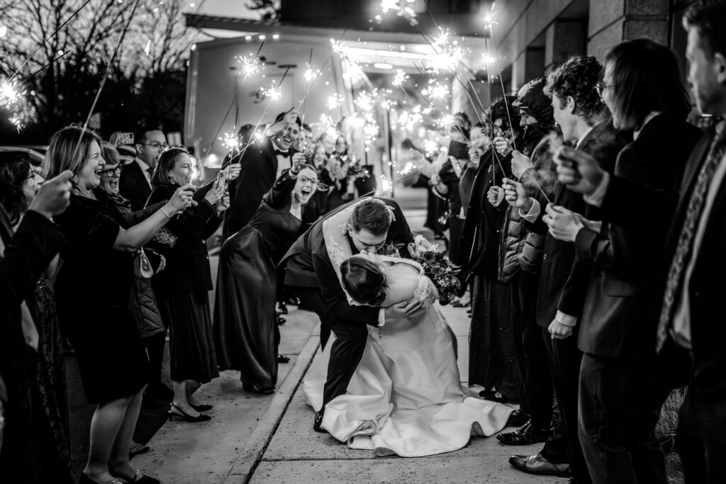 A bride and groom share a dramatic dip kiss surrounded by sparklers during a Christmas themed wedding in Herndon Virginia