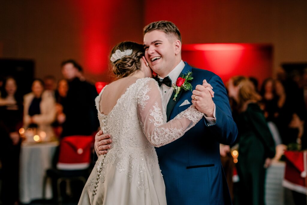 A groom smiles as he dances with his bride