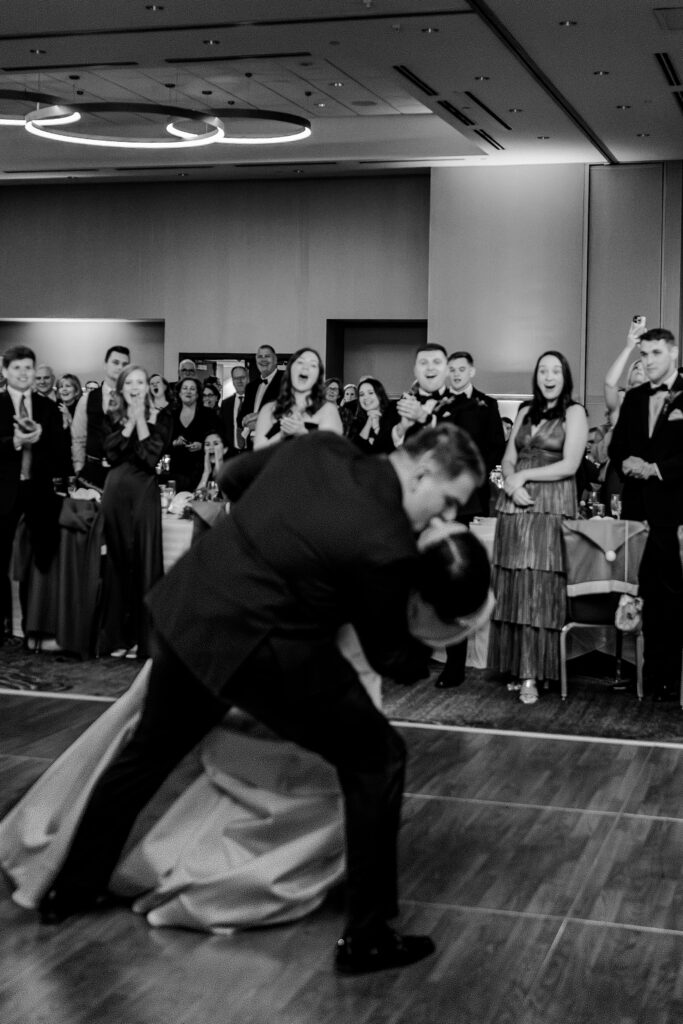 A crowd cheers as the groom dips the bride during their First Dance