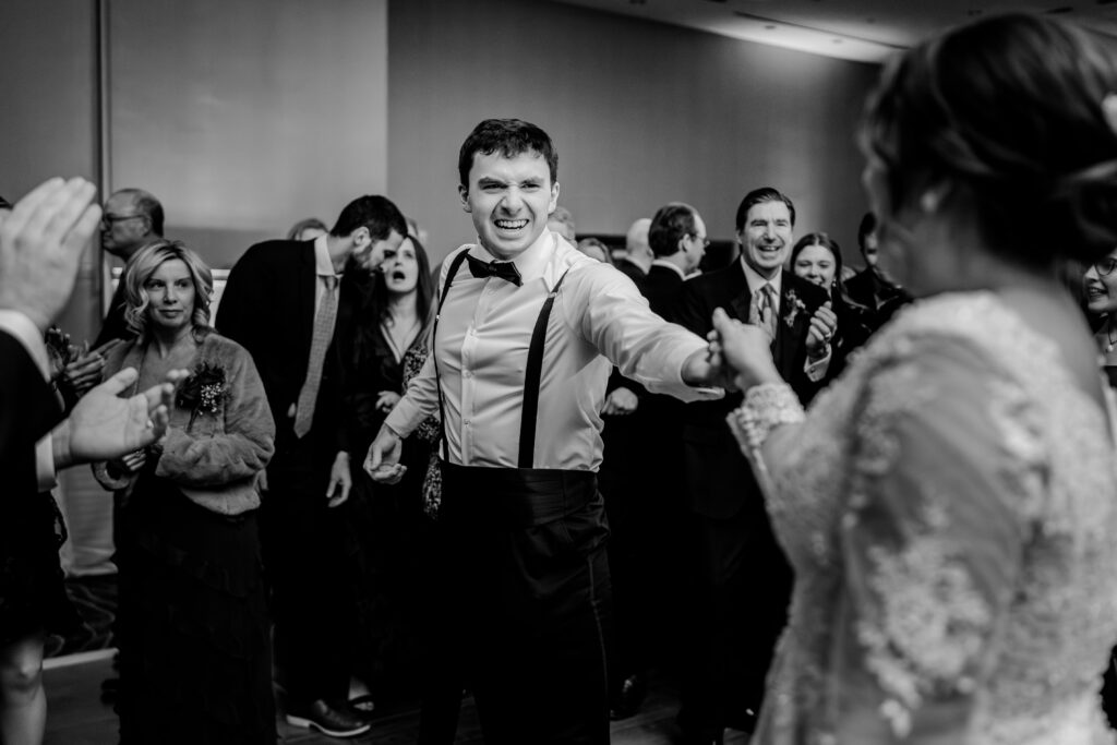 A guest smiles as he dances with the bride