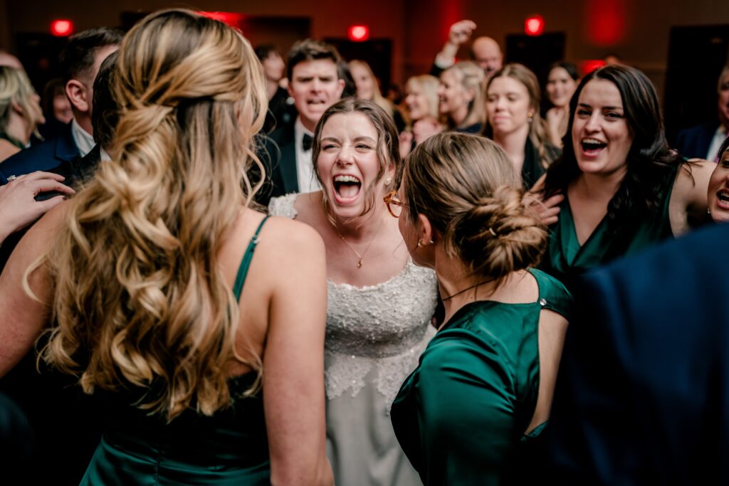 A bride laughs as she dances with her friends