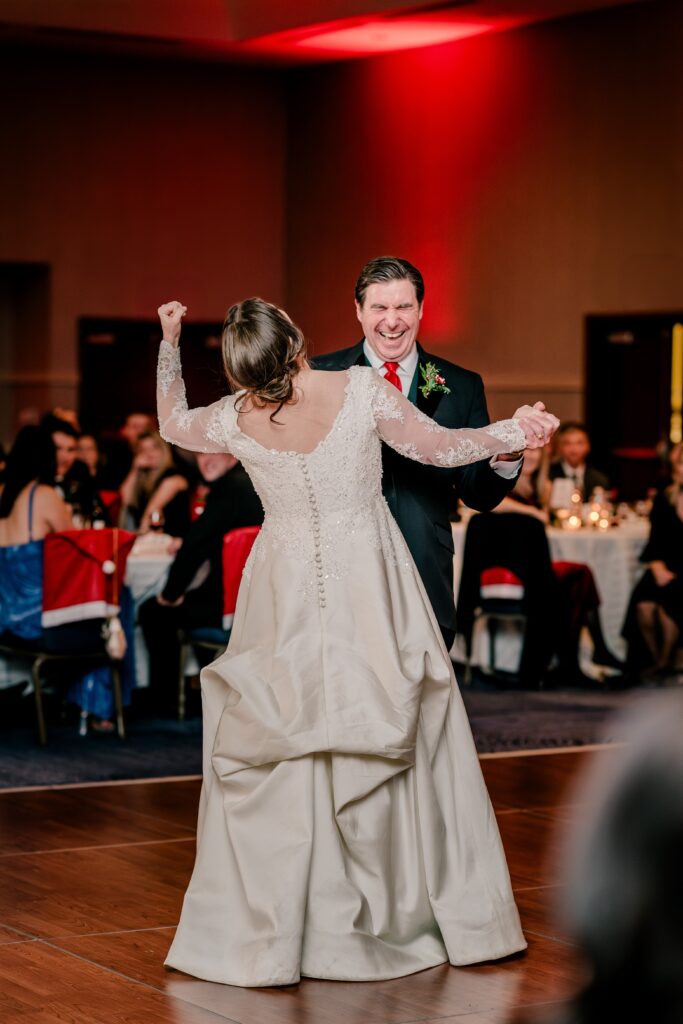 A bride and her father laugh as they dance together