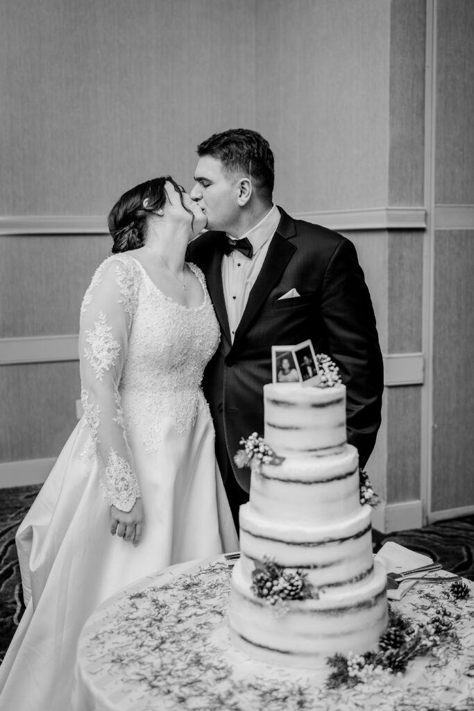 A bride and groom share a kiss after cutting their wedding cake