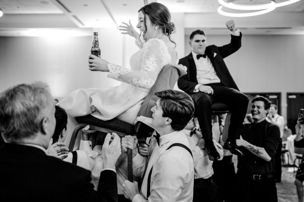 A bride and groom are lifted up by guests during a Christmas themed wedding at the Hyatt Regency Dulles in Herndon Virginia