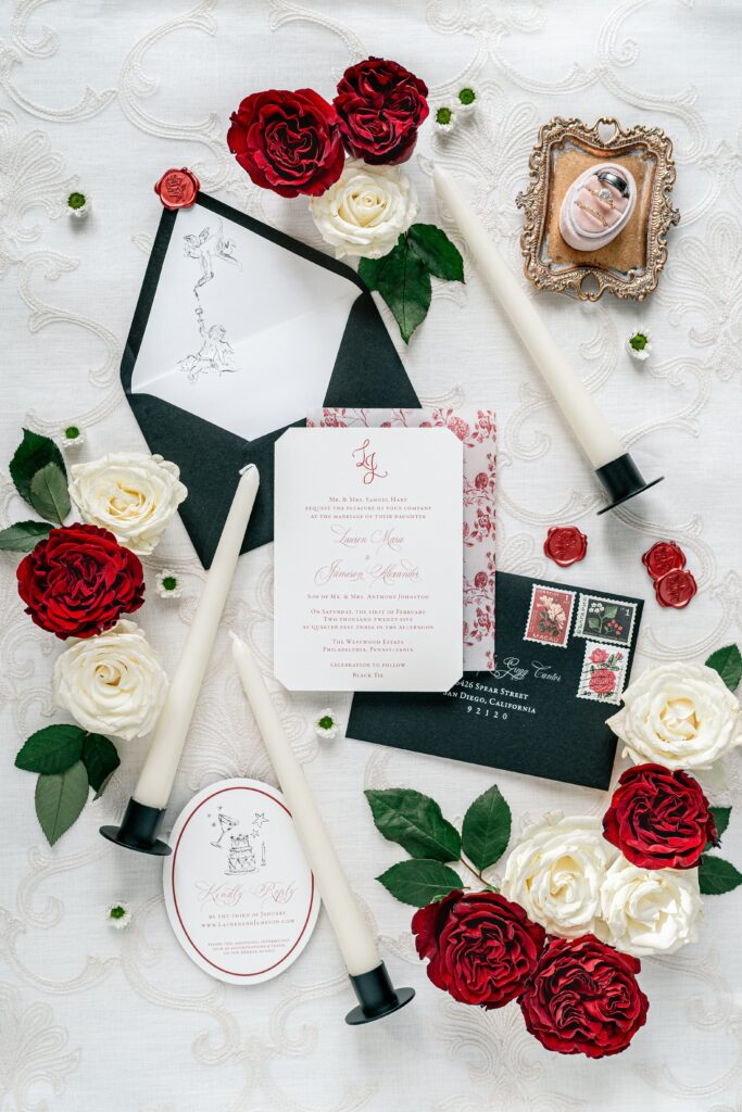 Wedding flat lays featuring a red and black invitation suite complemented by candles and roses