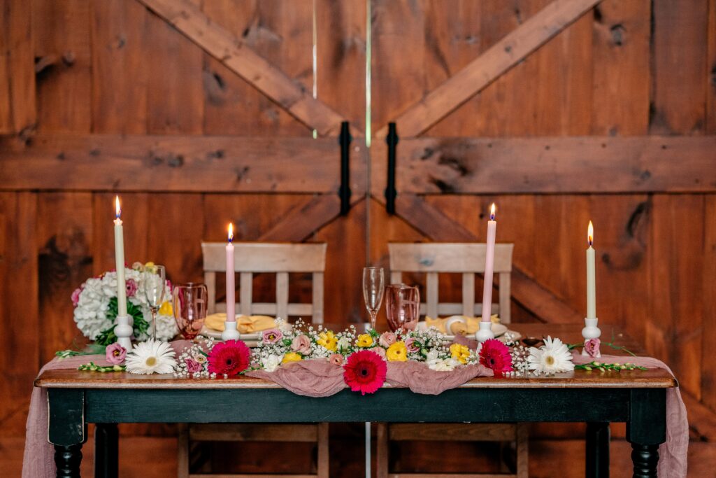 A close up of a sweetheart table for a wedding featuring colorful pink and yellow flowers