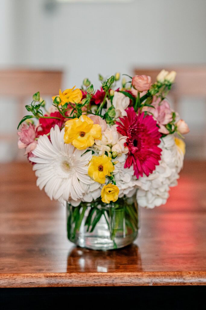 A floral arrangement by Mystical Rose Flowers featuring vibrant pink and yellow flowers