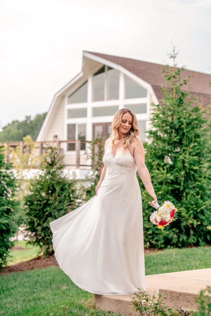 A bride twirling her skirt in front of Halcyon Watson, a modern barn wedding venue in Leesburg Virginia