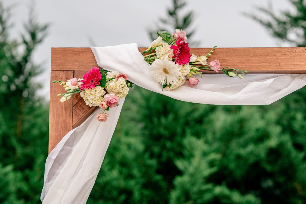 A ceremony arch decorated with pink and white flowers