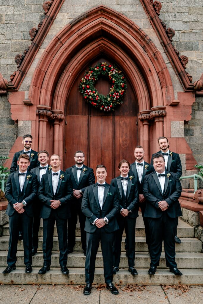 Groomsmen pose for a group portrait outside the church