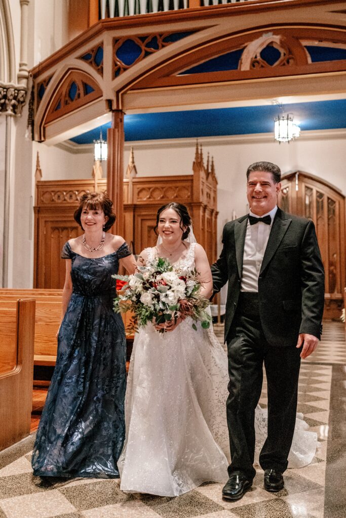 A bride and her parents walking down the aisle together
