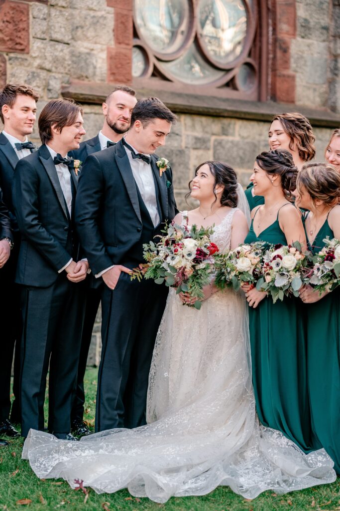 A bride and groom smiling at one another surrounded by their bridal party during their St Dominic DC wedding