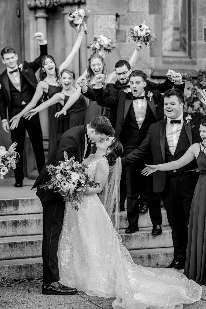 A wedding party cheers are the bride and groom share a kiss during their DC Christmas wedding