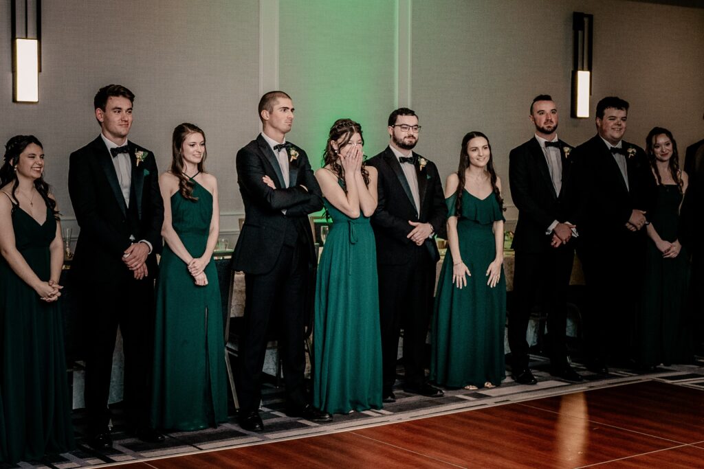 Wedding party members reacting with joy to the bride and groom's first dance