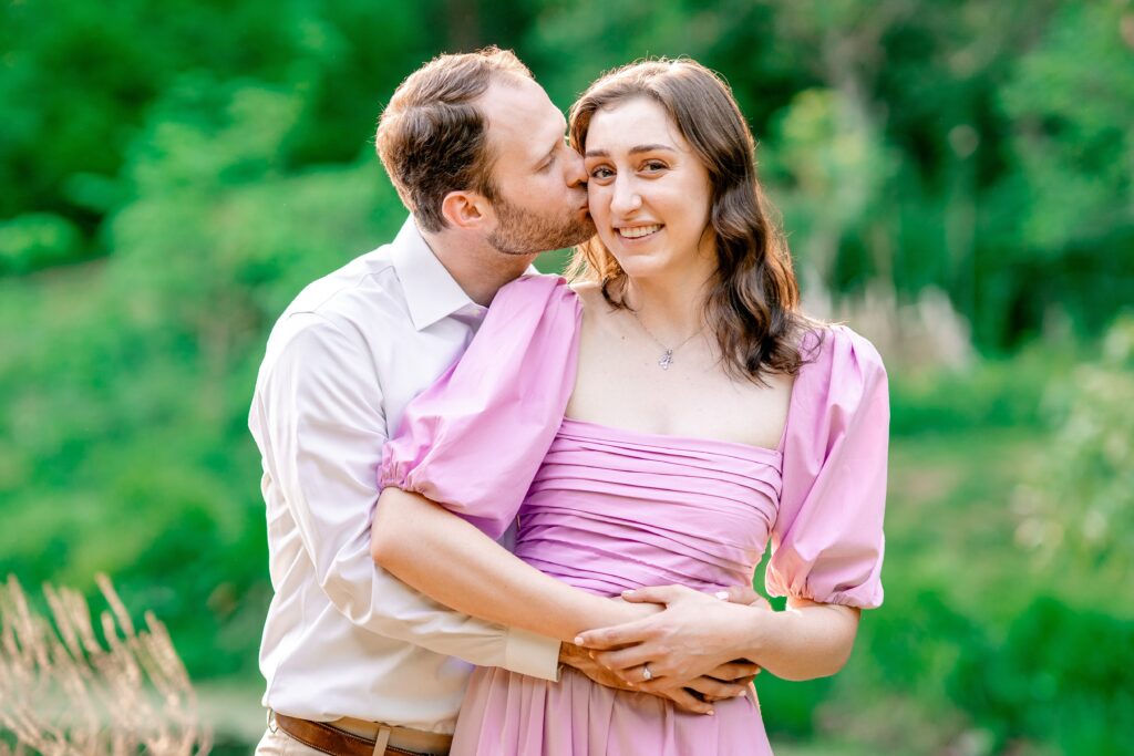 A man kisses his fiancee on the cheek
