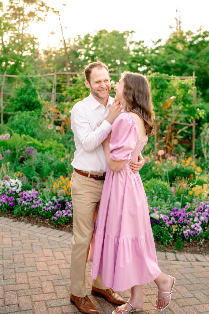 An engaged couple laughing together surrounded by purple and orange flowers