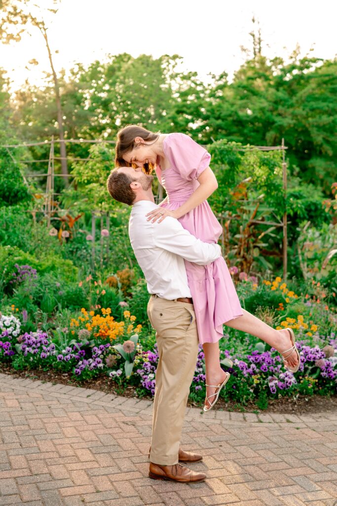 An engaged couple forehead to forehead as the man lifts her off the ground