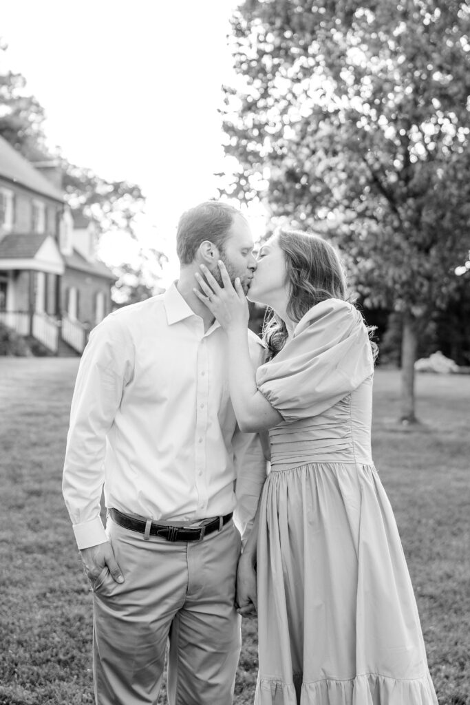 An engaged couple share a kiss in black and white
