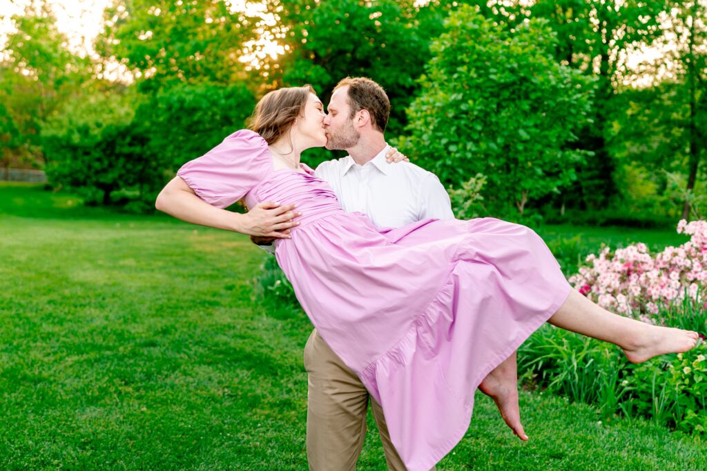 A couple shares a kiss as he holds her in his arms during their photos at at one of the best garden venues in Northern Virginia