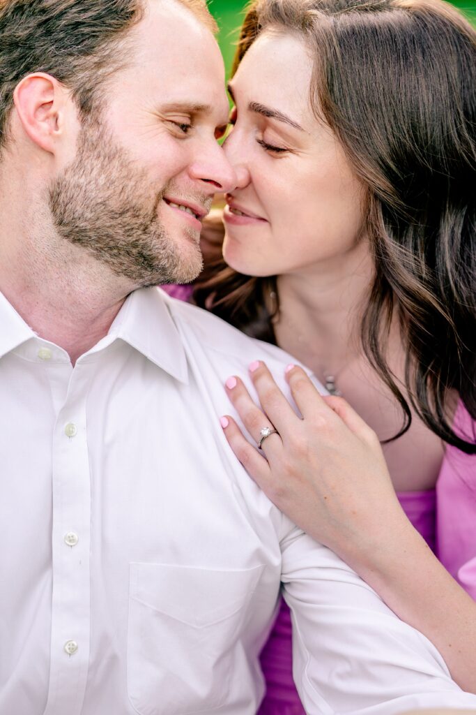 A close up of an engaged couple nuzzling together