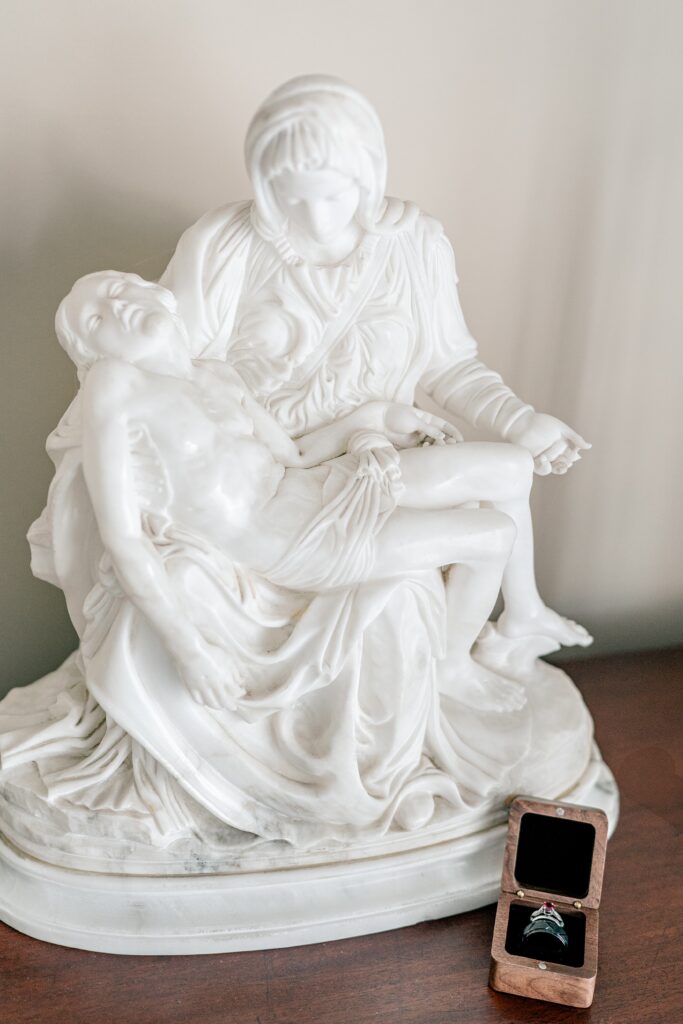 A set of wedding rings sitting beside an image of the Pieta