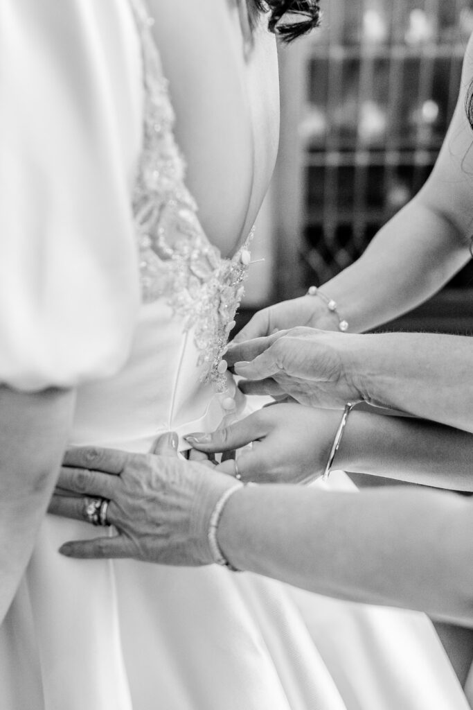 A bride's mother and sister helping button her dress before her Union Street Public House wedding