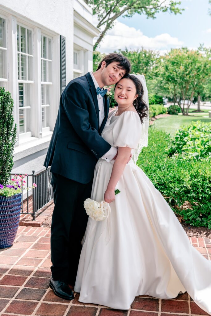 A bride and groom pose for a classic portrait in front of the Main House during their Marymount University wedding