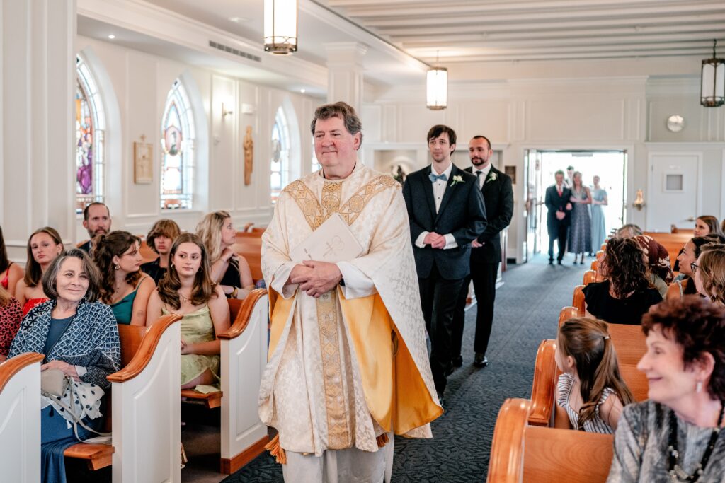 A priest leading the groom and best man into the wedding ceremony