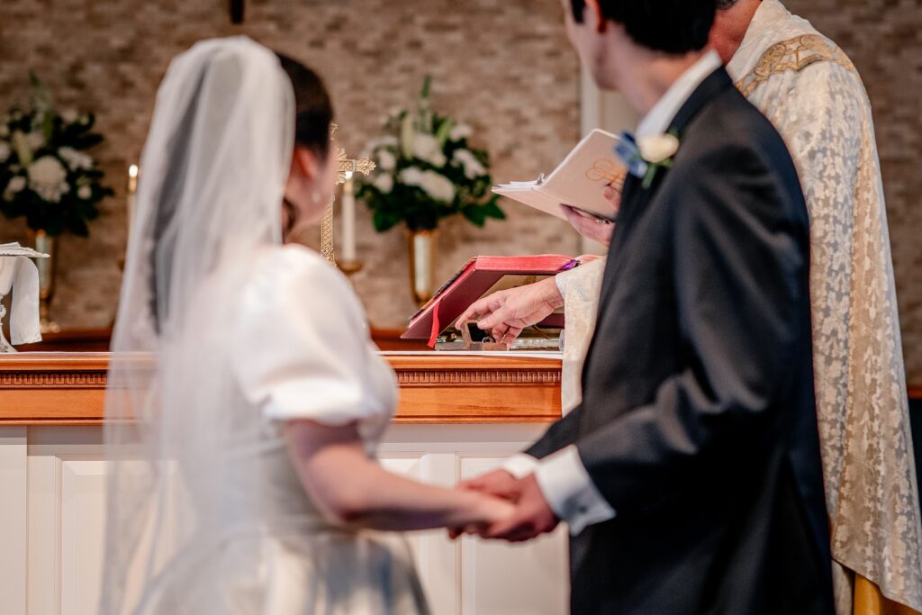 A priest holding the rings before the bride and groom 