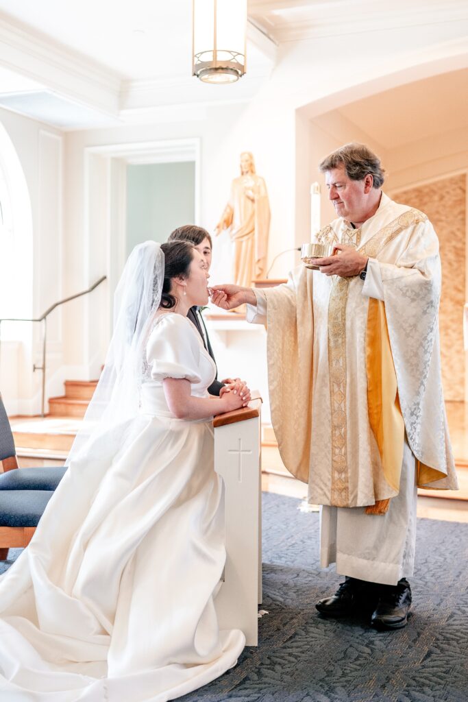 A bride receiving Communion during her Catholic wedding