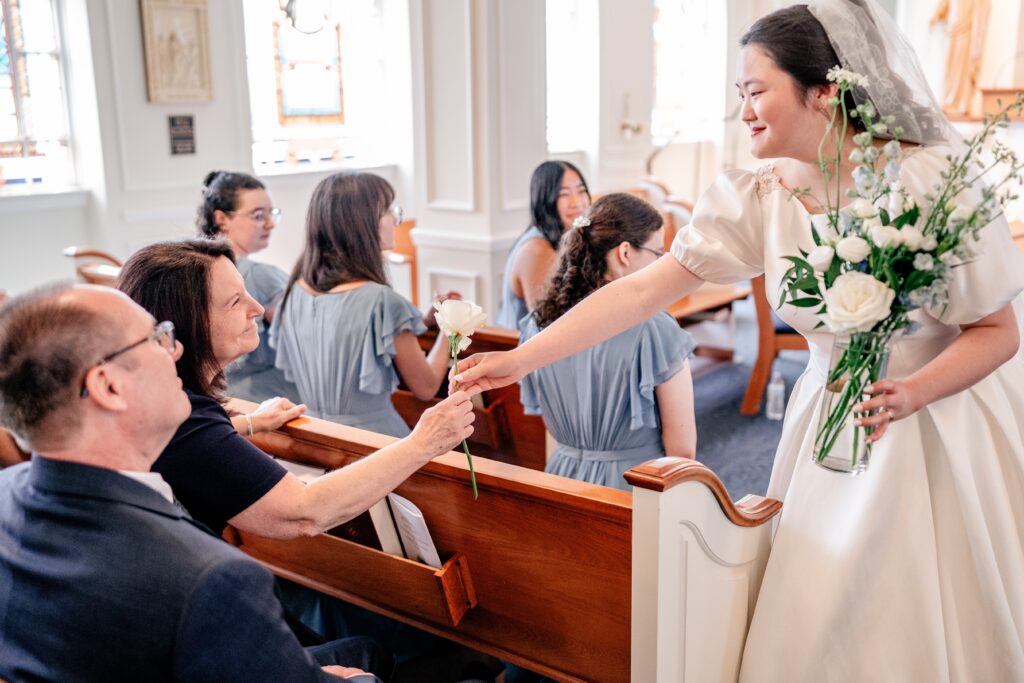 A bride handing her mother a rose during her Marymount University wedding