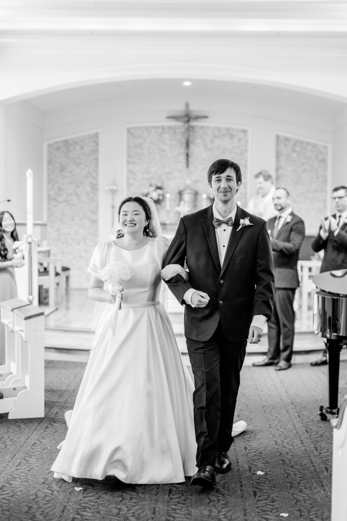 A bride and groom smiling as they leave their ceremony