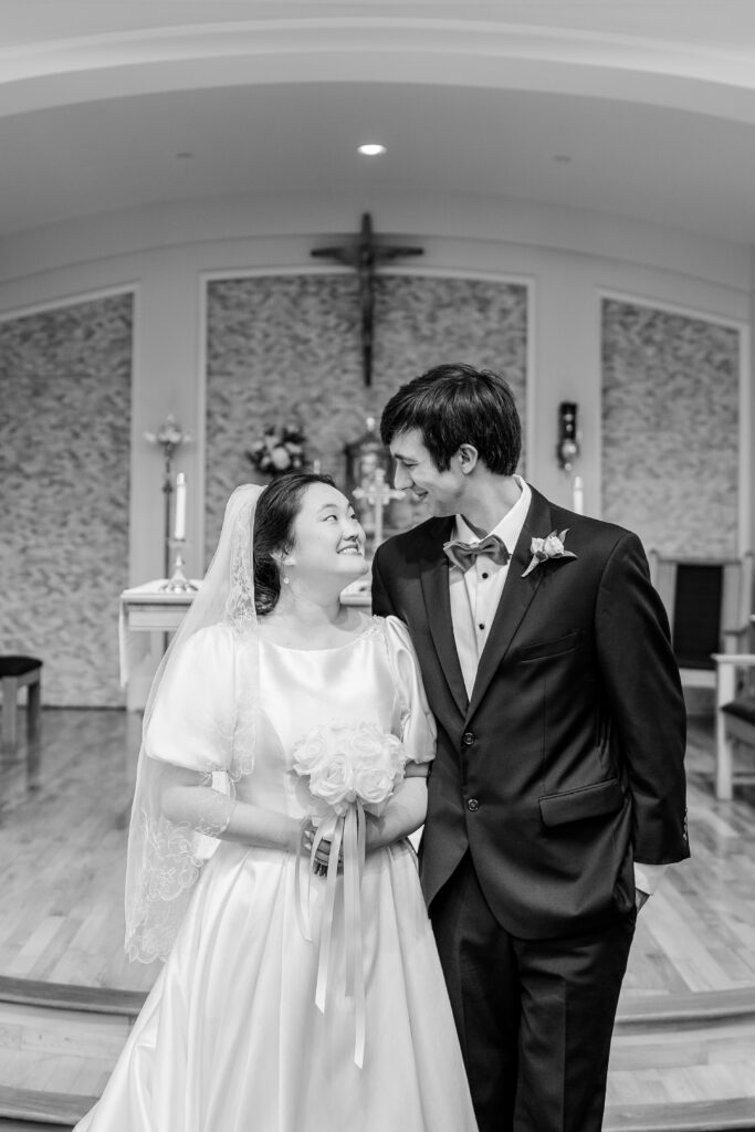 A bride and groom smiling at one another after their Catholic wedding