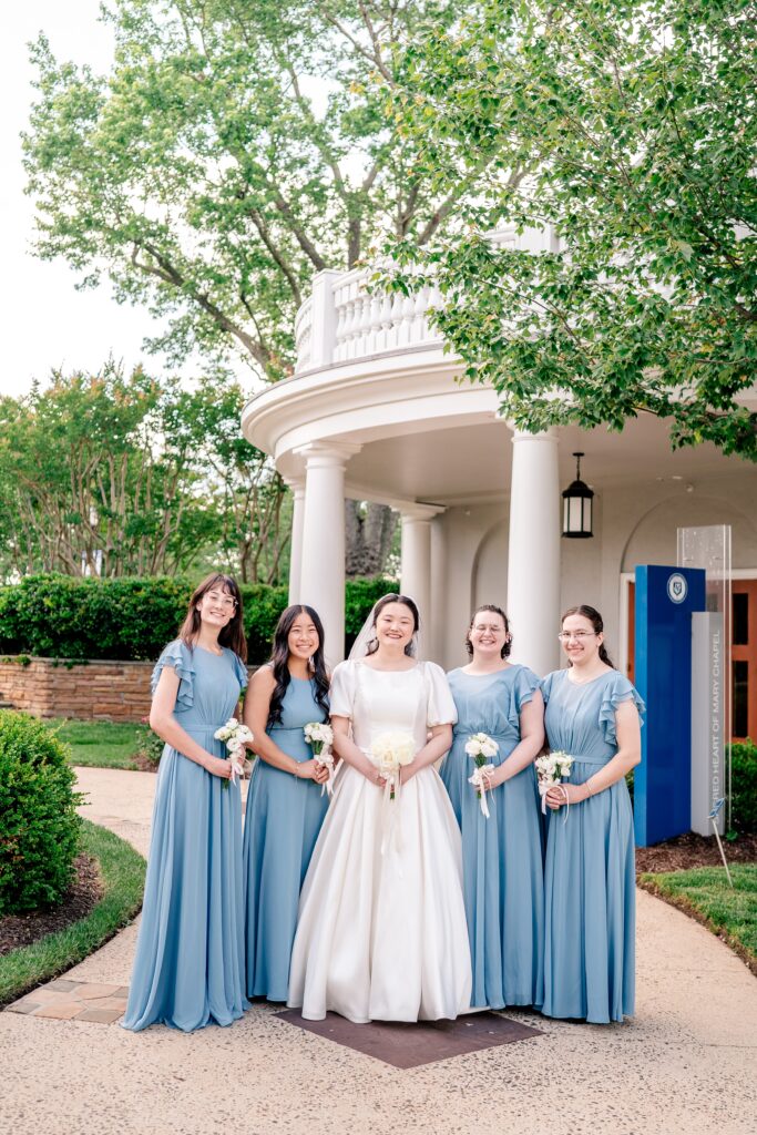 A bridal party posed in front of the chapel