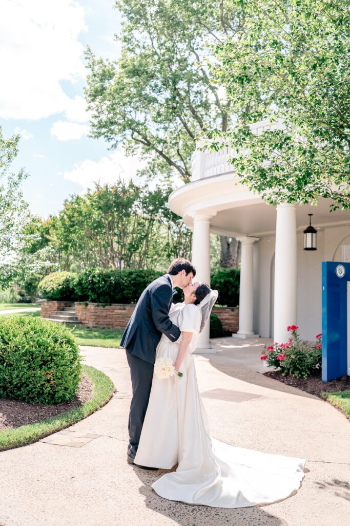 A bride and groom share a kiss in front of the chapel