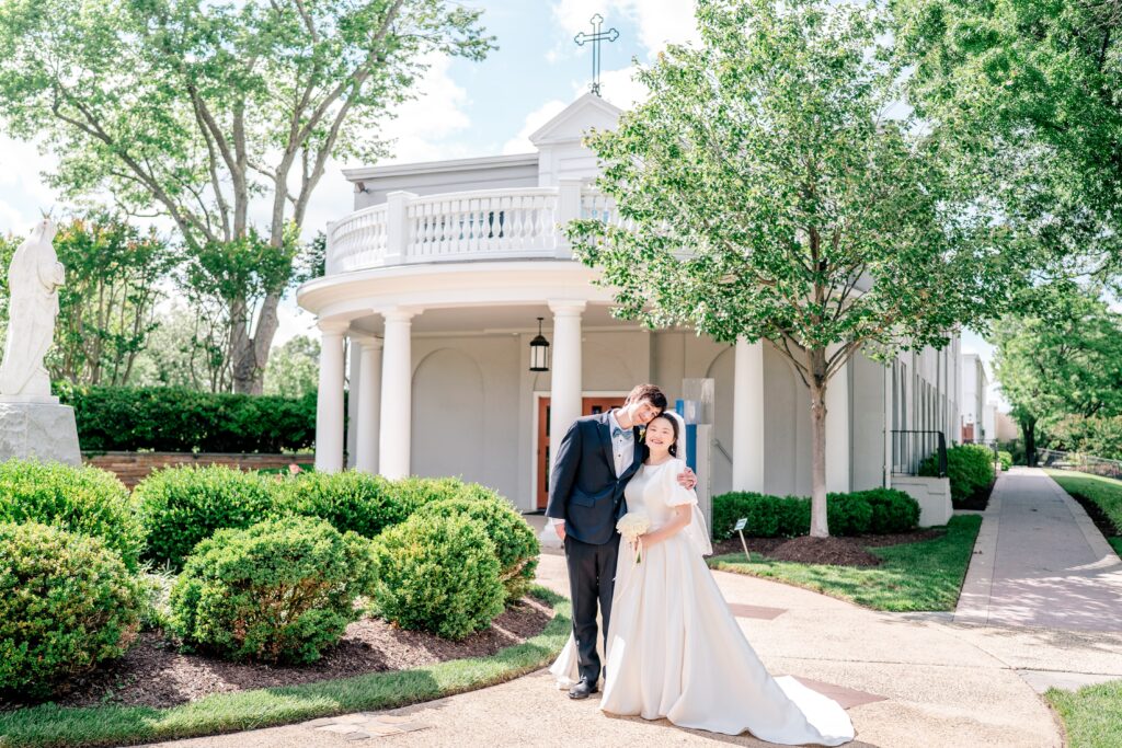 A bride and groom posed traditionally in front of the chapel by Northern Virginia wedding photographer