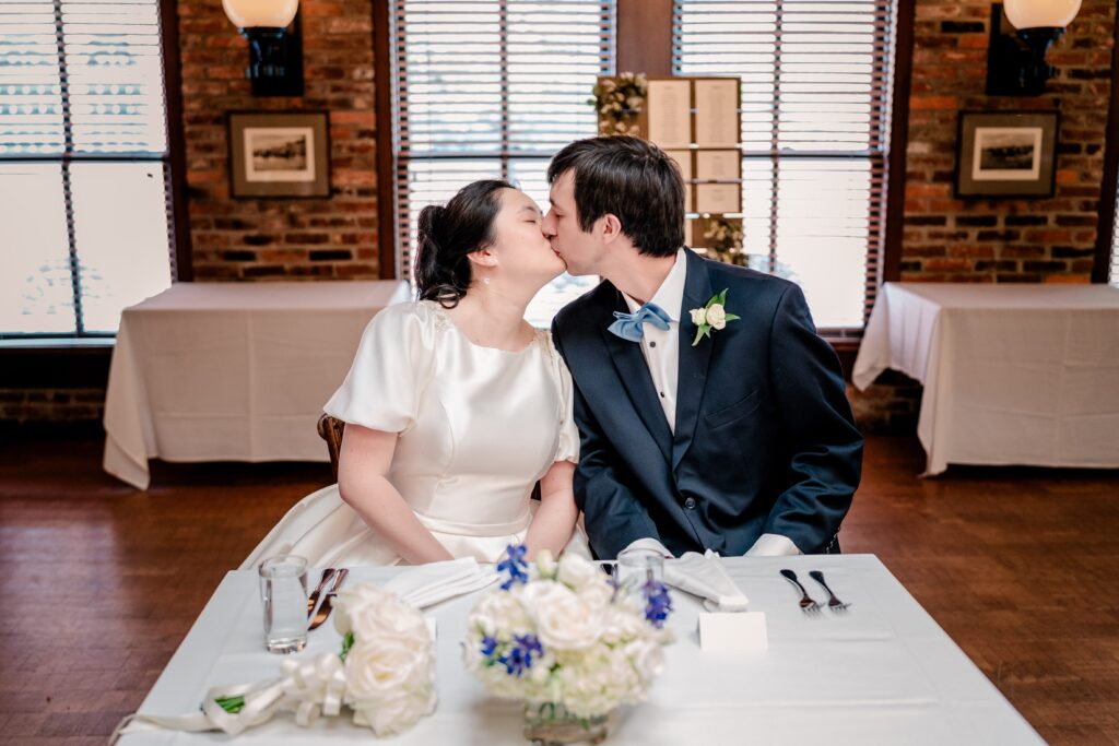 A bride and groom share a kiss at their sweetheart table during a Union Street Public House wedding