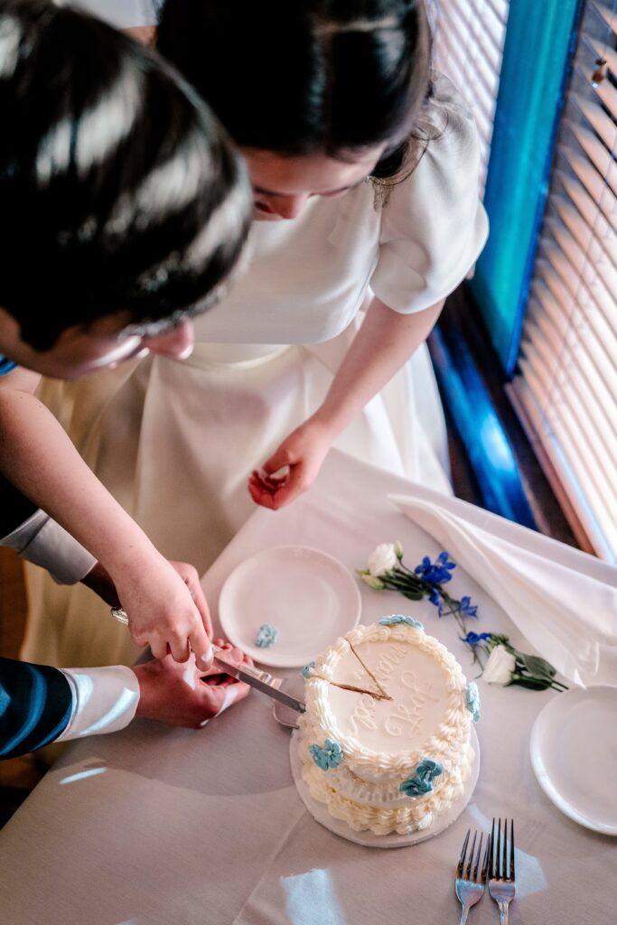 A bride and groom cut a buttercream frosted cake during their Union Street Public House wedding