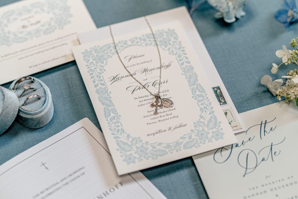 An invitation suite with a bride's necklace resting on top for a Greek Orthodox wedding