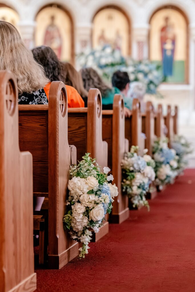 Floral arrangements on pews for a Greek Orthodox wedding
