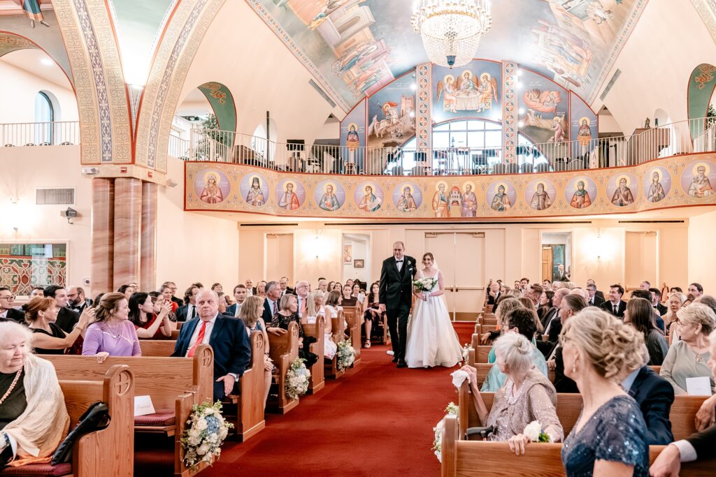 A bride and her dad walking down the aisle inside a church