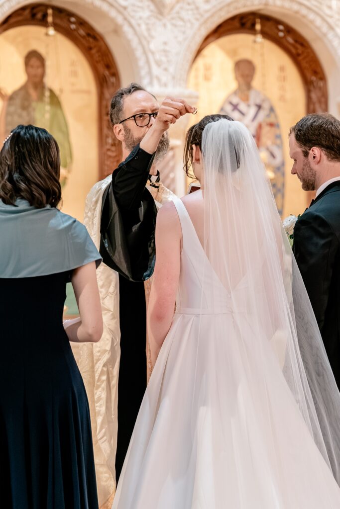 A priest holding a ring over the bride's head during their ceremony