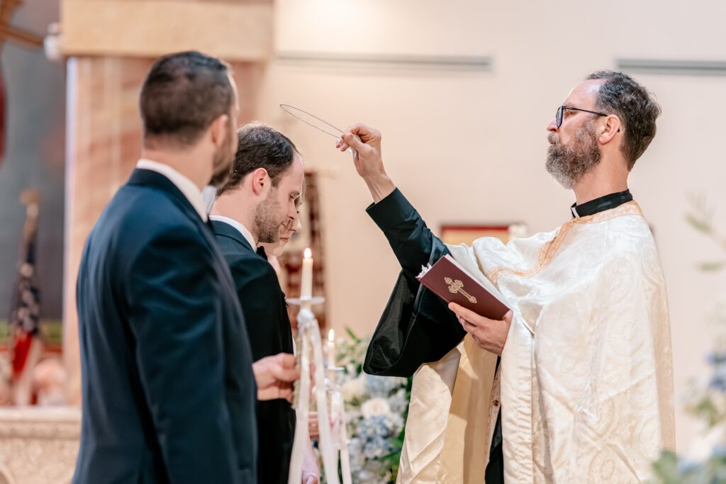 A priest crowning the bride and groom for a colorful wedding photographer