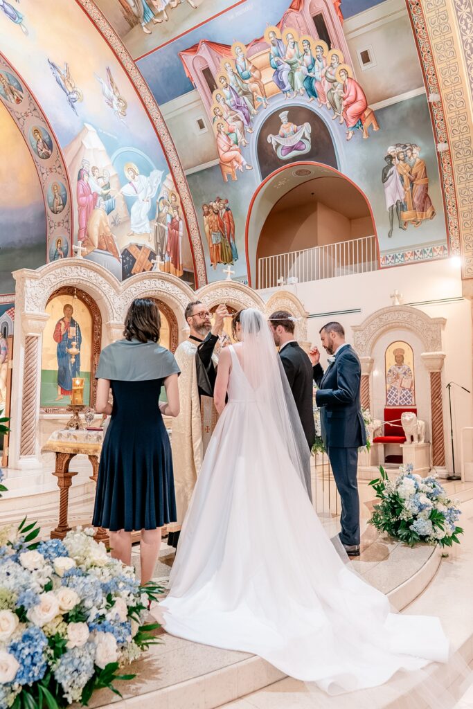 A priest holding a crown over the bride's head during their religious wedding ceremony