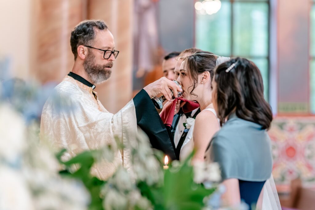 A bride drinking from the cup during a Greek Orthodox wedding