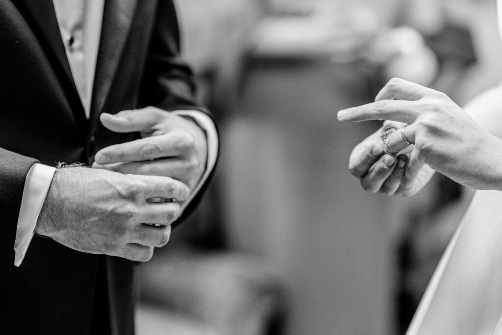 A bride and groom playing with the rings on their fingers by a colorful wedding photographer