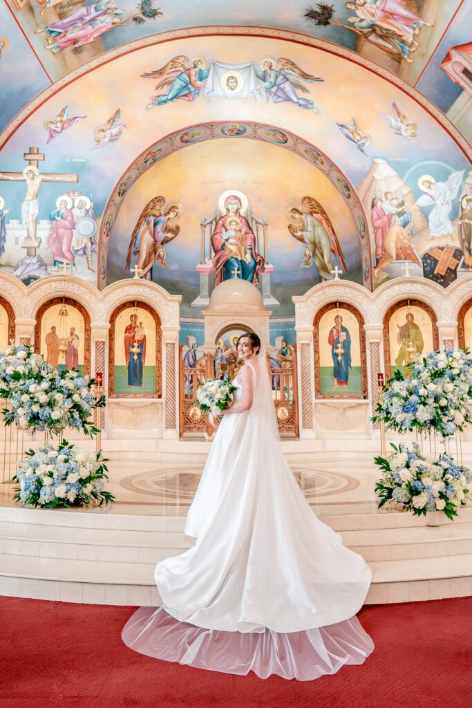 A bride showing off her long train and veil at the front of her church