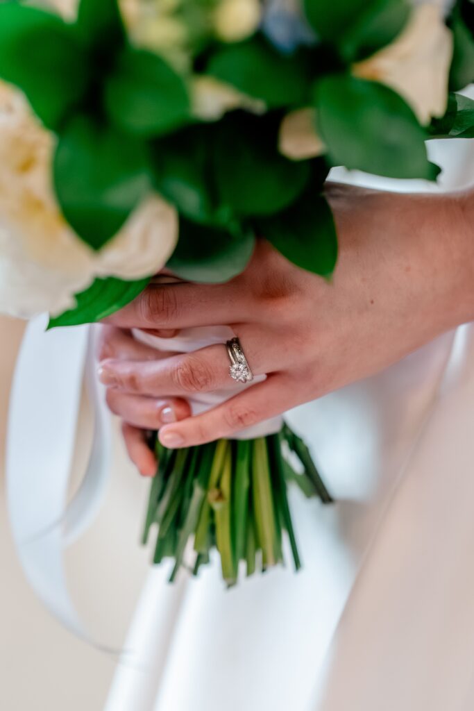 A close up of a bride's rings on her hands holding her bouquet